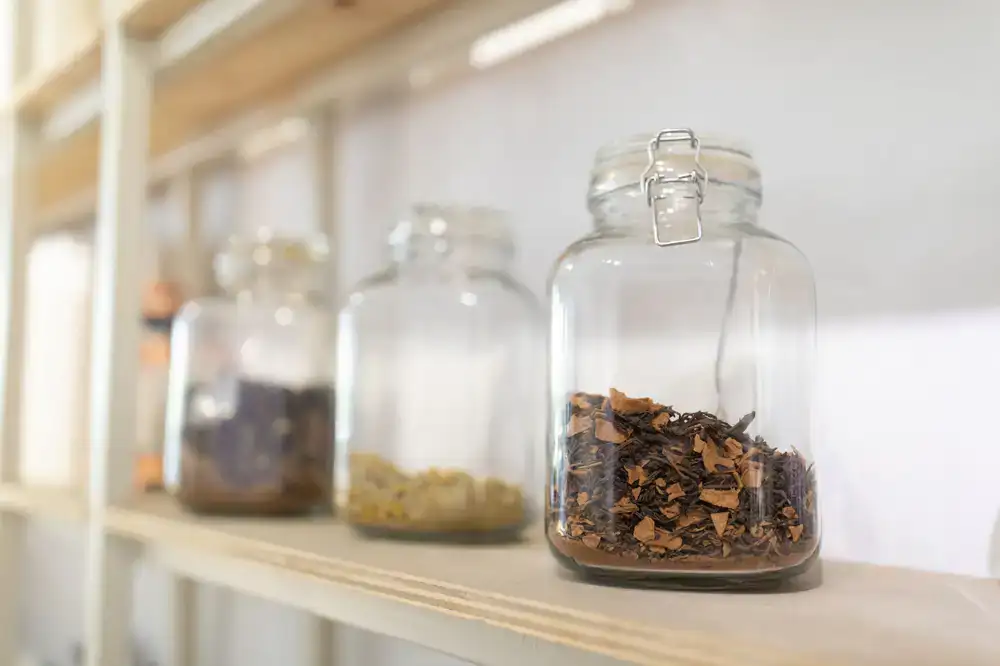 Glass jars of dried herbs on wooden shelves