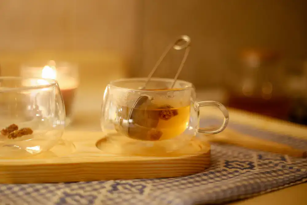 Steaming cup of herbal infusion with a strainer