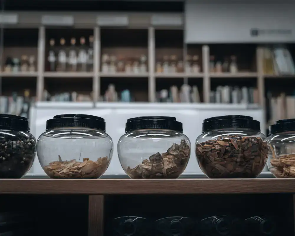 Glass jars filled with dried herbs lining a wooden apothecary shelf